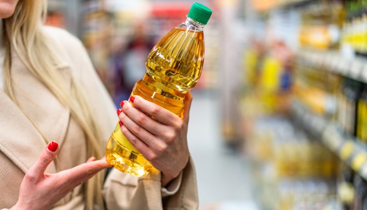 Vrouw in de supermarkt met een fles zonnebloemolie in haar hand