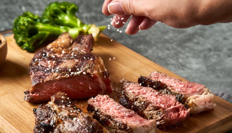 Man bestrooit steak met zout