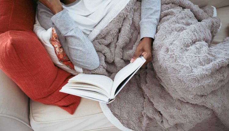 Vrouw met warmtedeken op de bank