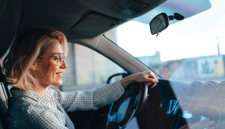 Oudere vrouw achter het stuur van de auto, lachend