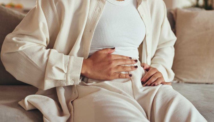 Vrouw met hand op haar buik omdat ze pijn heeft