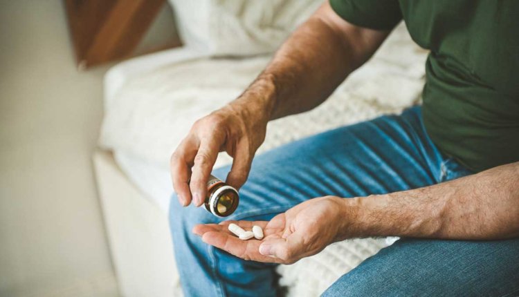 Man zit op rand van het bed neemt erectiepil