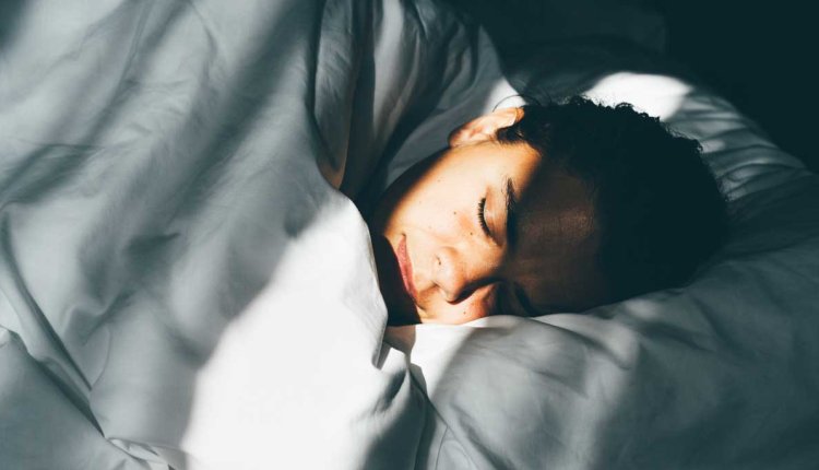 Vrouw ligt lekker te slapen in haar bed in het ochtendzonnetje