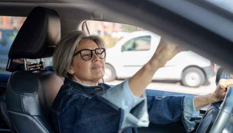 Vrouw zit in de auto en checkt haar uiterlijk