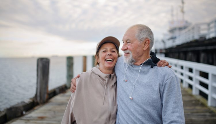 Man en vrouw lopen lachend over pier