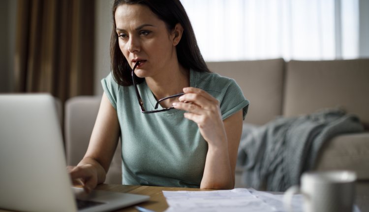 Vrouw in groene sweater is thuis bezig met belastingzaken achter laptop