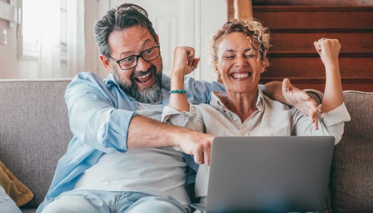 Vrouw en man zien dat ze de loterij gewonnen hebben op laptop
