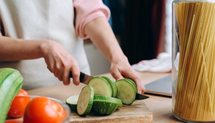 Een vrouw is courgette aan het snijden op een snijplank