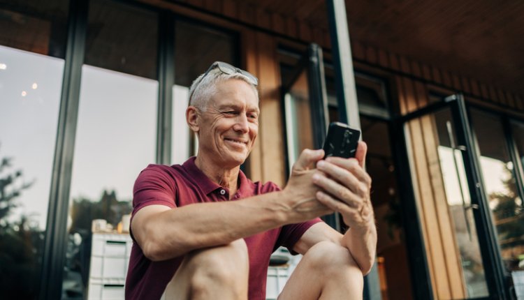 Man speelt met smartphone op veranda vakantiehuis