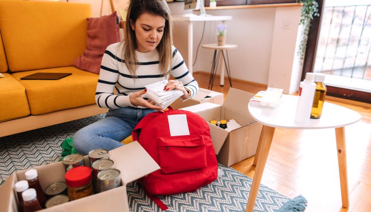vrouw stelt noodpakket samen in de woonkamer