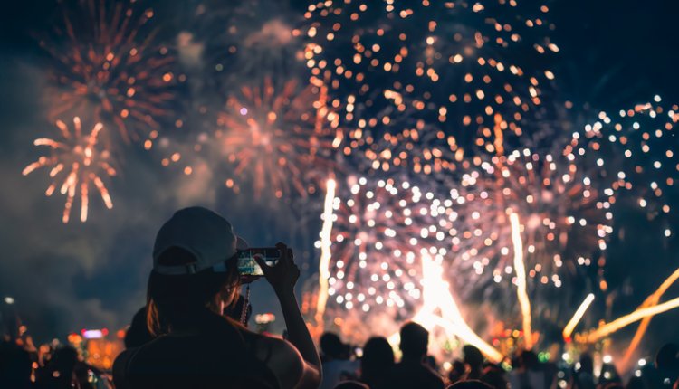 Vrouw kijkt met telefooncamera naar vuurwerkshow