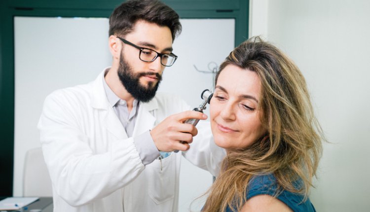 Oorarts kijkt in oor bij vrouw