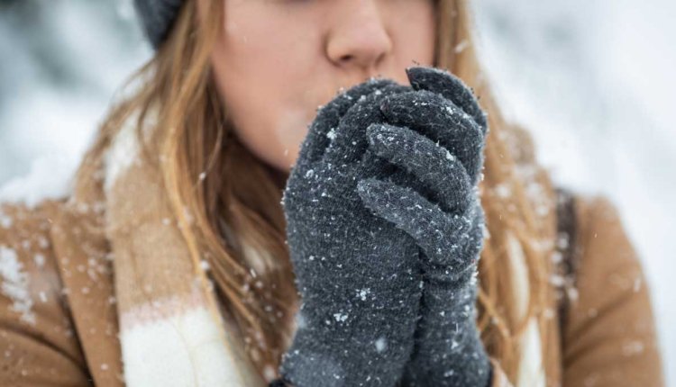 Vrouw heeft koude handen in haar handschoenen want het sneeuwt