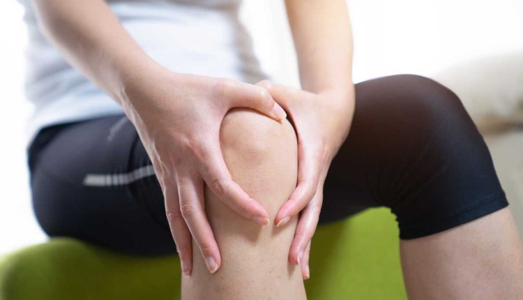 Vrouw met haar handen om haar pijnlijke knie