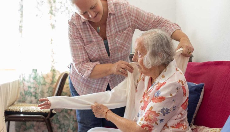 Vrouwelijke mantelzorger helpt oudere dame