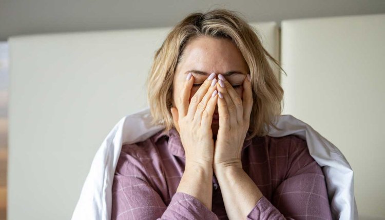 Vrouw zit vermoeid op bed na een slechte nacht slapen