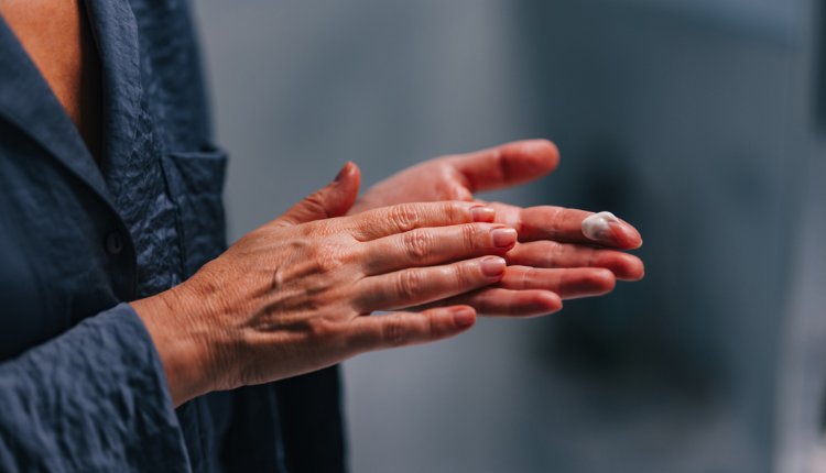oudere vrouw smeert handen in