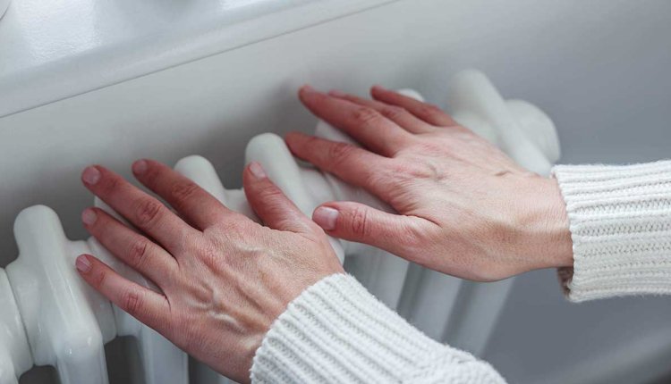 Vrouw warmt haar handen aan de verwarming
