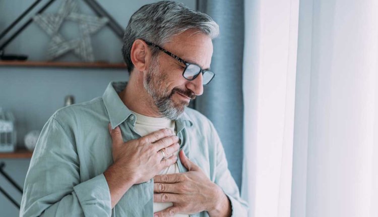 Man grijpt naar zijn borst. Hij heeft pijn. Is het zijn hart?
