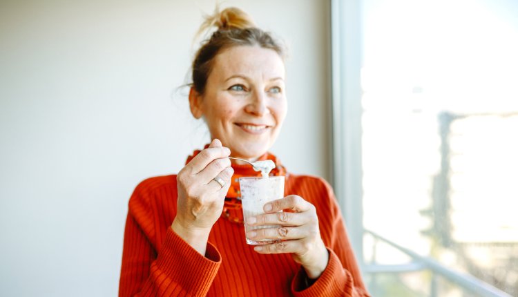 lachende vrouw eet yoghurt