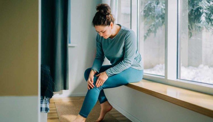 Vrouw voelt aan haar knie die zeer doet