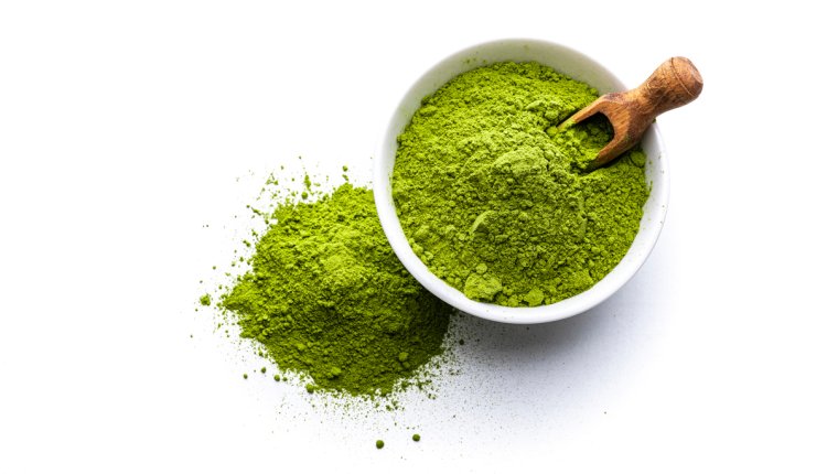 Matcha in een potje met een houten lepel op een witte achtergrond