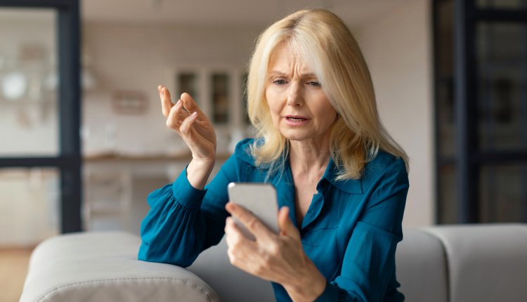 vrouw kijkt zorgelijk naar telefoon