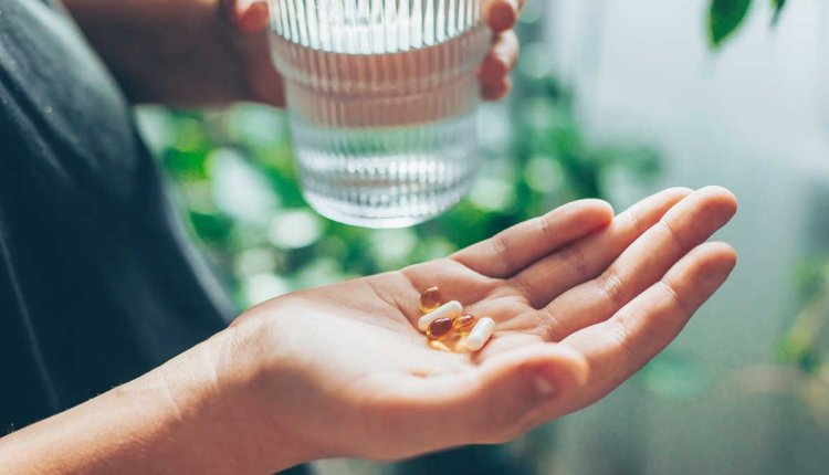 vrouw met glas water en vitamines