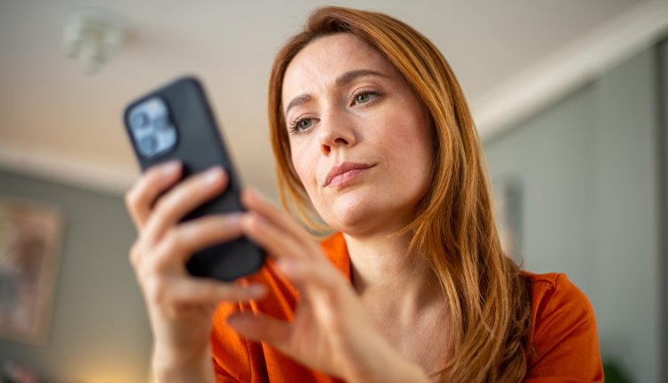 Vrouw met lang rood haar checkt smartphone