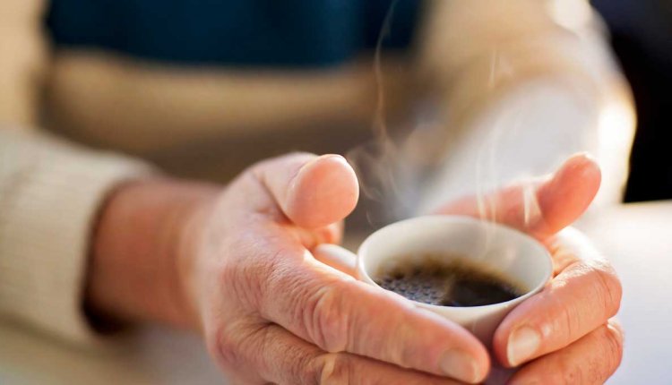 Vrouw warmt haar handen aan een kop koffie