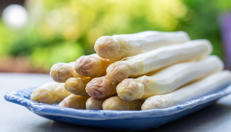 Witte asperges liggend op een blauw bord