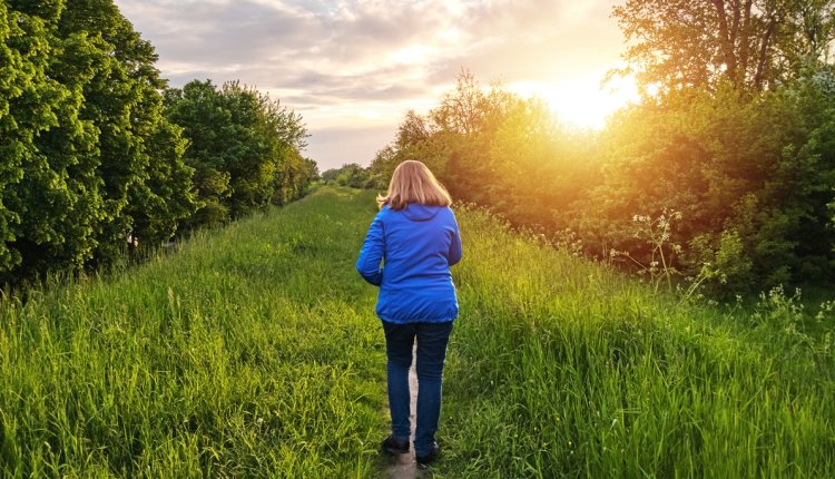 Vrouw loopt over dijk in het opkomende zonnetje