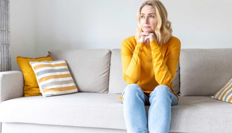 Vrouw zit op de bank en denkt na