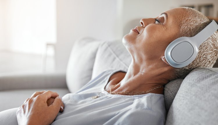 Vrouw ligt op de bank en luistert naar een podcast