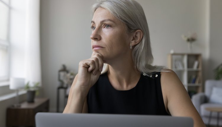 Vrouw zit achter laptop, onzeker over oplichters