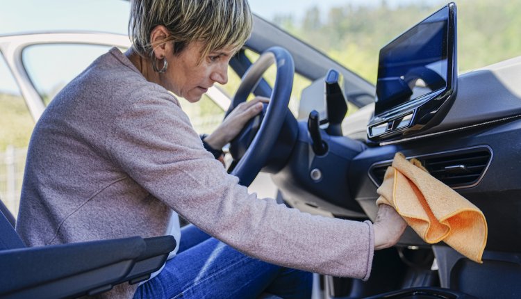 oudere vrouw maakt auto van binnen schoon