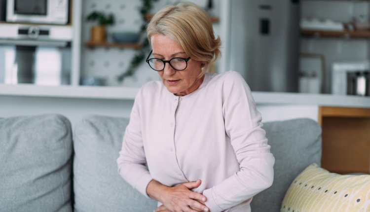 Vrouw met handen op haar buik vanwege pijn