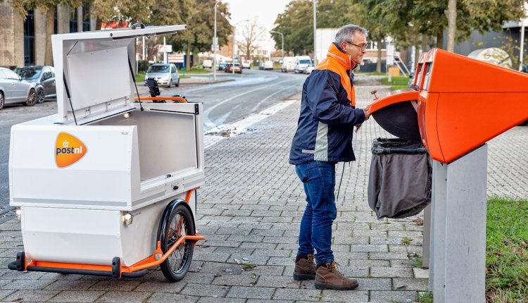 Postbezorger leegt oranje brievenbus