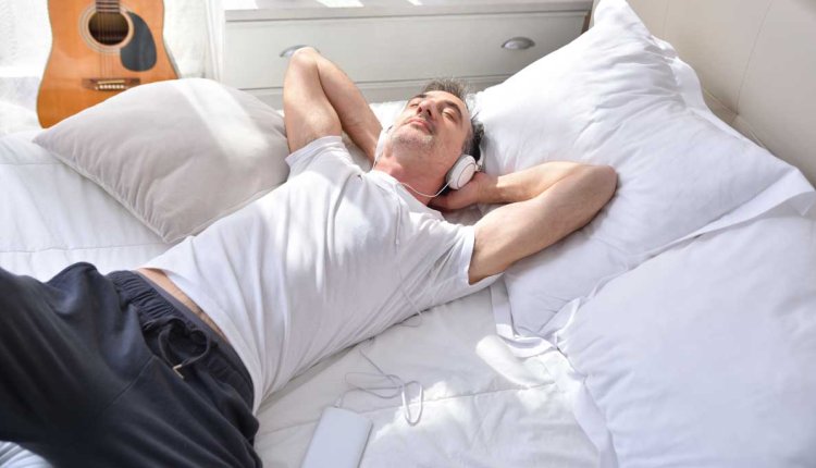 Man ligt op bed met koptelefoon