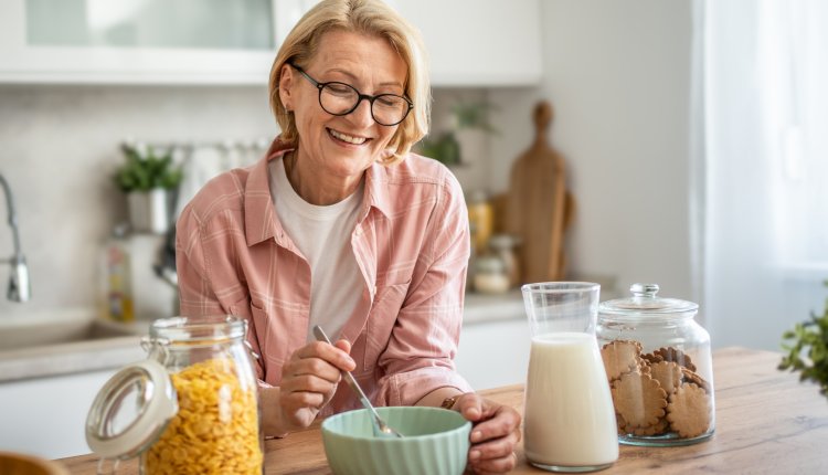 Vrolijke vrouw eet havermout in de keuken