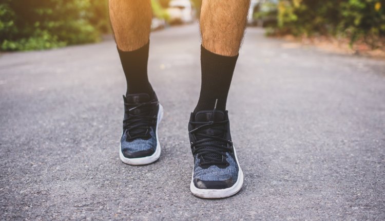 Man op gympen loopt op straat