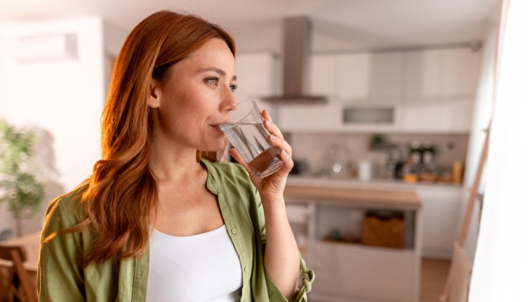 Vrouw drinkt een glas water omdat ze last heeft van de hik