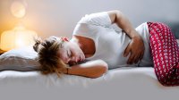 Vrouw met buikpijn in bed