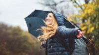 vrouw loopt buiten in de regen met paraplu in de herfst