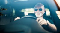 Oudere man met zonnebril achter het stuur