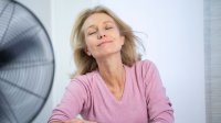 Vrouw zit voor ventilator af te koelen
