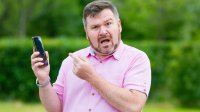 Man is boos en verongelijkt aan de telefoon in de tuin