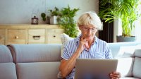 Uitkering in gevaar, vrouw kijkt bezorgd op laptop