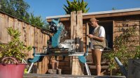 Man is bezig met hout zagen, schuur op de achtergrond