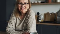 Vrouw leunt op aanrecht in de keuken